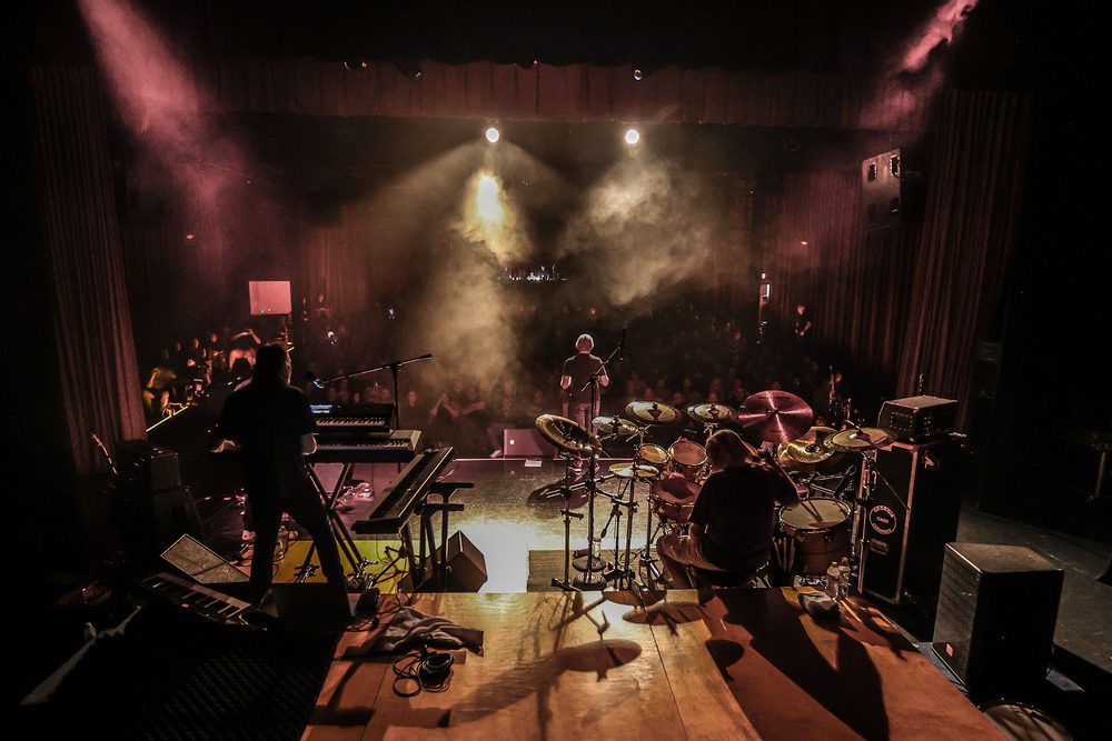 A full band on the concert stage in blue light